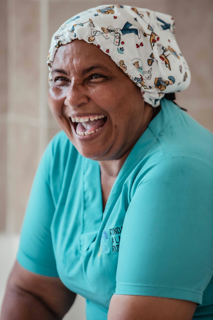 A research coordinator in scrubs and a surgical cap laughing