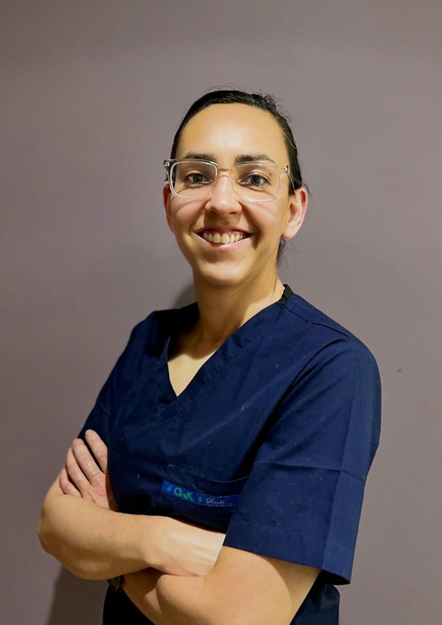 A smiling research nurse in blue scrubs and glasses